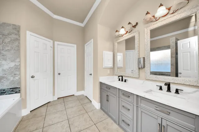 a spacious bathroom with a double vanity sink mirror and bathtub