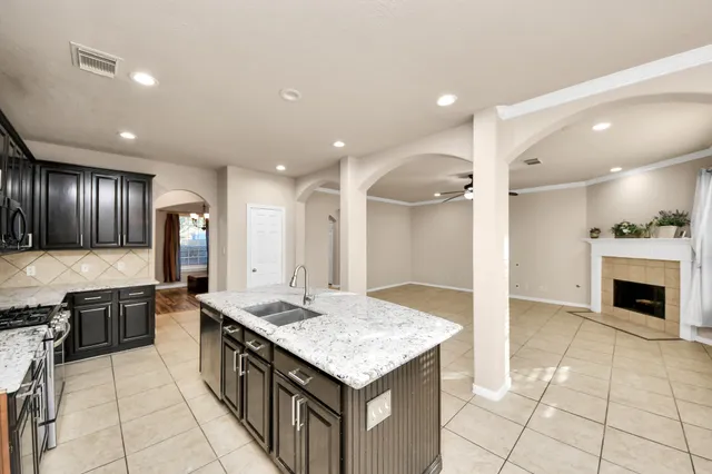 a kitchen with granite countertop a stove a sink and a refrigerator