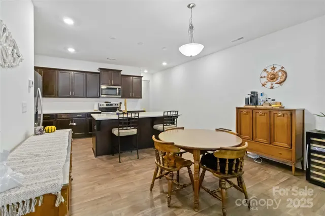 a kitchen with stainless steel appliances a dining table chairs and stove top oven