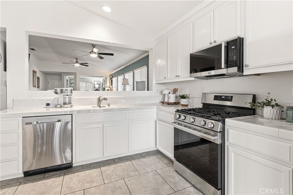 1478 La Sierra Street Merced, CA 95348 - Photo 10 of 32 a kitchen with stainless steel appliances granite countertop a sink dishwasher a stove and a microwave oven with cabinets