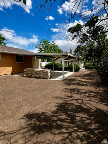 1766 Kenilworth Road Spring Glen, UT 84526 - Photo 14 of 24 Backyard featuring a covered patio with a built-in stone fireplace, a rectangular concrete patio, and an expansive area of exposed earth