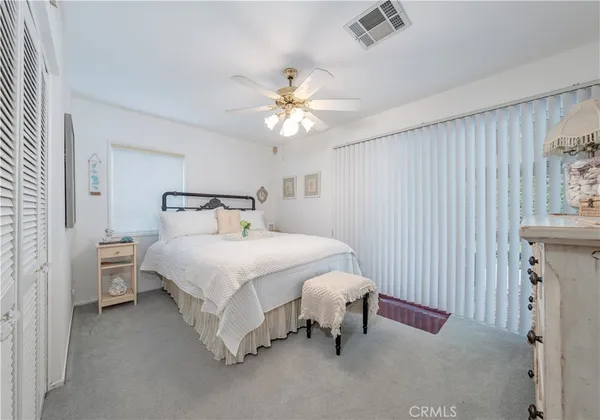a bedroom with a bed a dresser and a chandelier