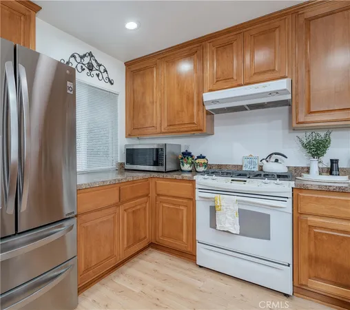 a kitchen with stainless steel appliances granite countertop a refrigerator stove and sink with wooden cabinets