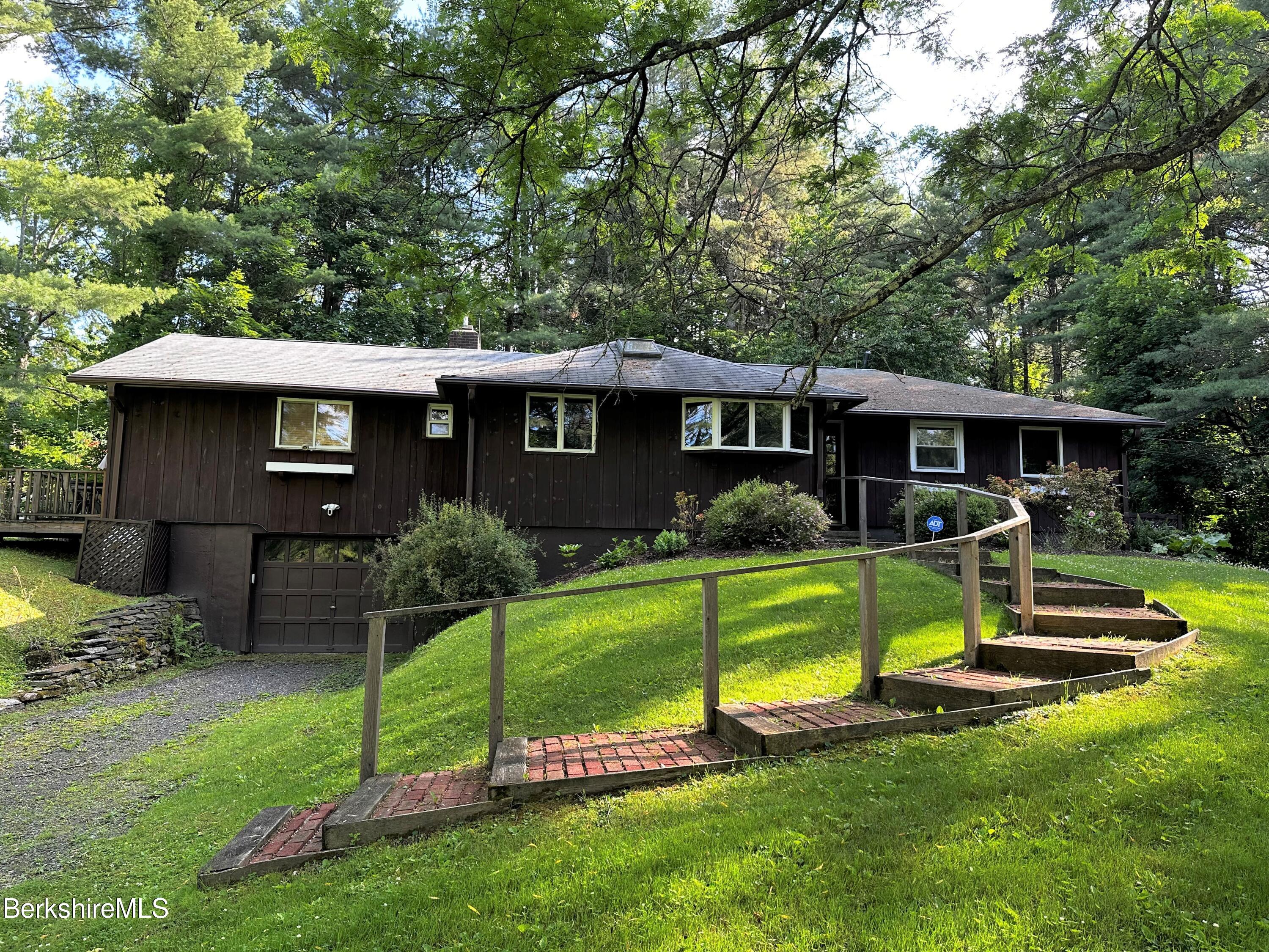 a view of a house with a yard and a large tree