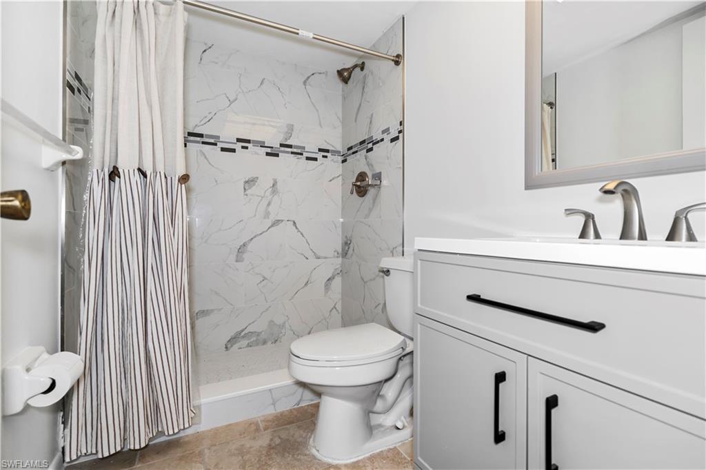 Bathroom with vanity and a marble finish shower