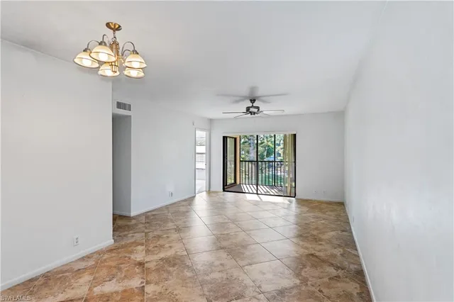 an empty room with chandelier and windows