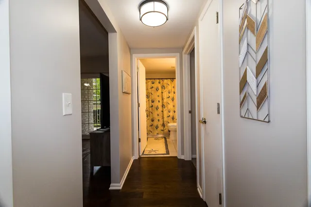a view of a hallway with wooden floor and a bathroom
