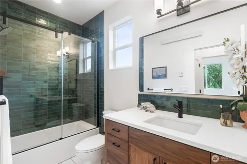 a bathroom with a shower sink vanity mirror and toilet