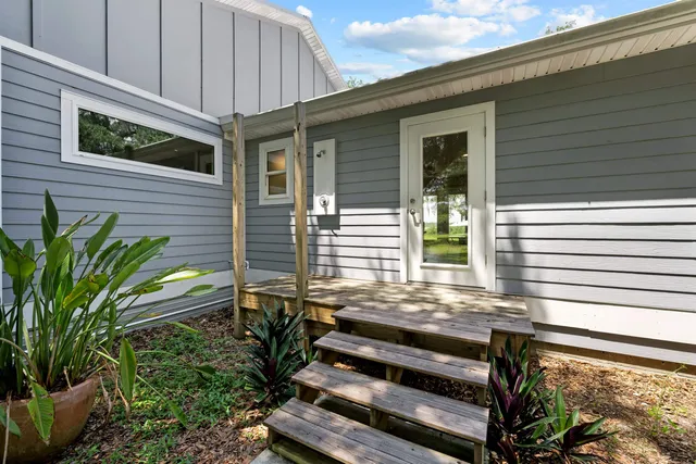 a view of a house with a small deck and a backyard