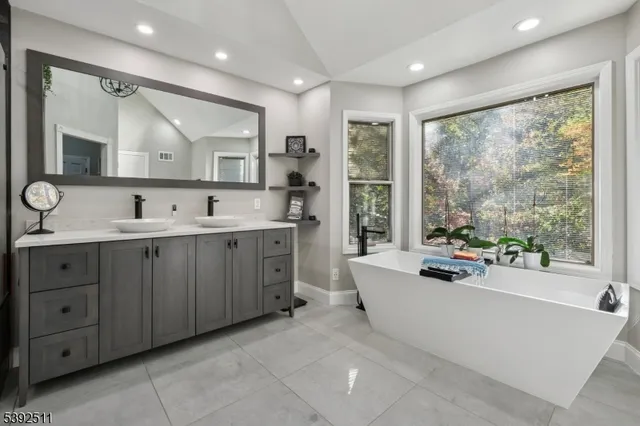 a spacious bathroom with a double vanity sink a large mirror and a bathtub
