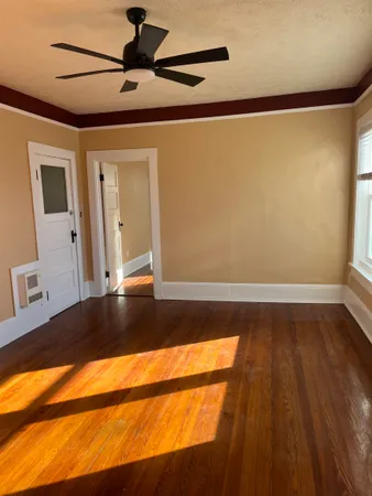a view of an empty room with wooden floor and a window