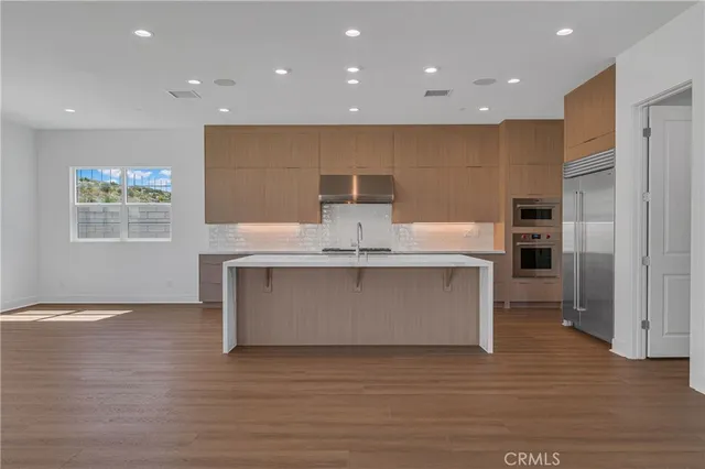 a view of kitchen with stainless steel appliances granite countertop a stove top oven a sink and a refrigerator