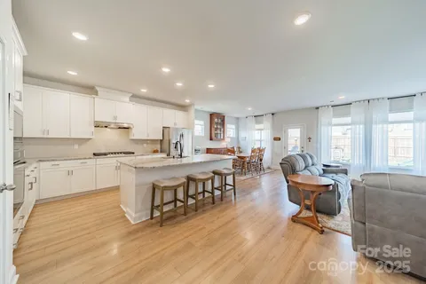 a living room with stainless steel appliances granite countertop furniture wooden floor and a kitchen view