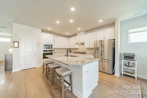a kitchen with stainless steel appliances kitchen island granite countertop a refrigerator and a sink