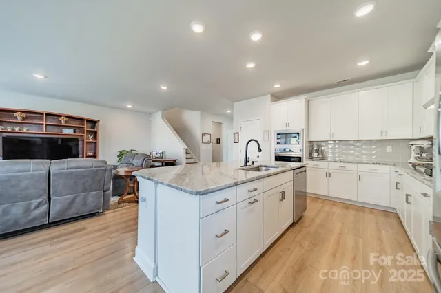 a large kitchen with a large counter top a sink a window and stainless steel appliances