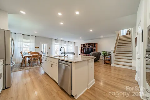 a large white kitchen with wooden floor and a dining table
