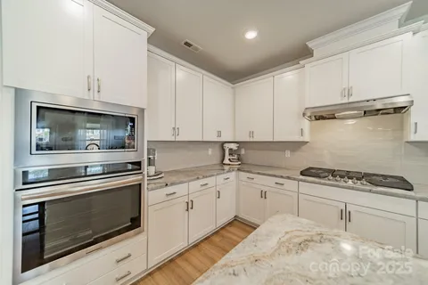 a kitchen with granite countertop cabinets stainless steel appliances and wooden floor