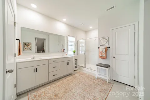a spacious bathroom with a double vanity sink a mirror and a bathtub