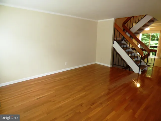 a view of an empty room with wooden floor and stairs
