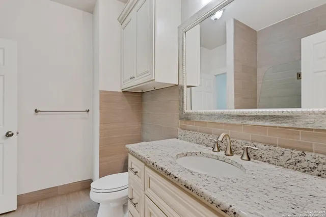 a bathroom with a granite countertop sink a toilet and shower