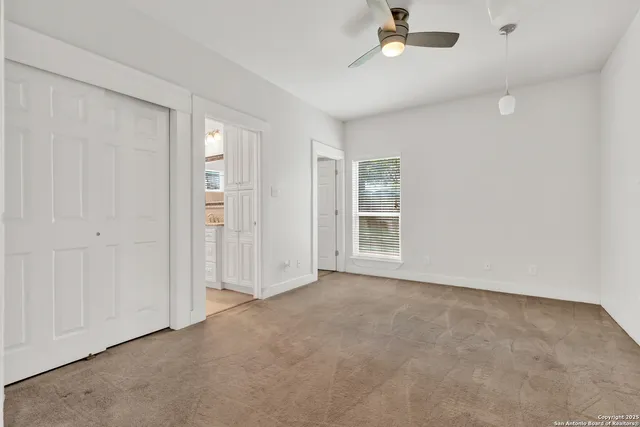 a view of an empty room and chandelier fan
