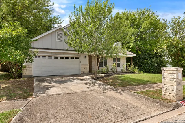 a view of a house with a yard and large tree