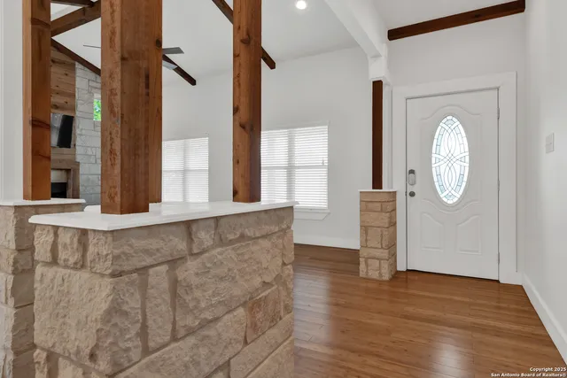 an empty room with wooden floor fireplace and windows