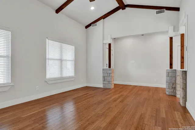 a view of empty room with wooden floor and fan