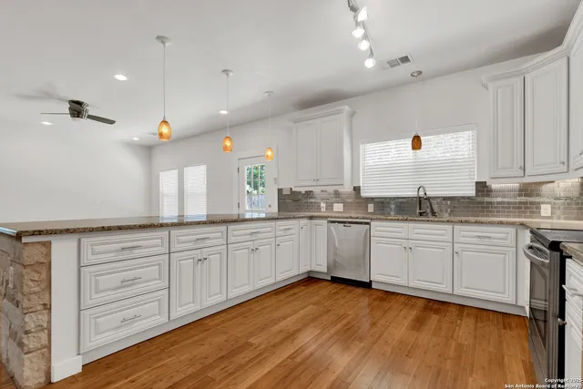 a large kitchen with granite countertop a sink a counter top space appliances and cabinets