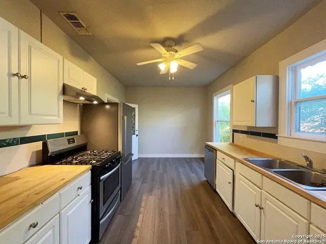 a kitchen with a sink a stove cabinets and wooden floor