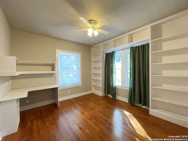 a view of an empty room with a window and wooden floor