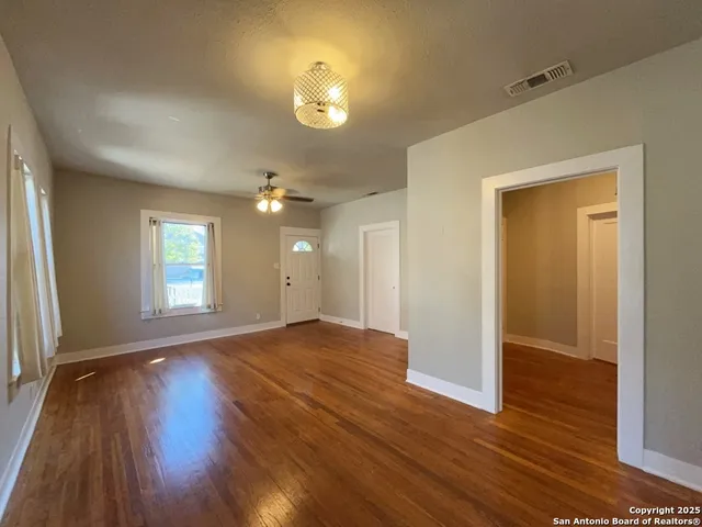 an empty room with wooden floor and windows