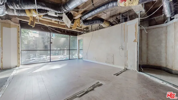 a view of an empty room with wooden floor and windows