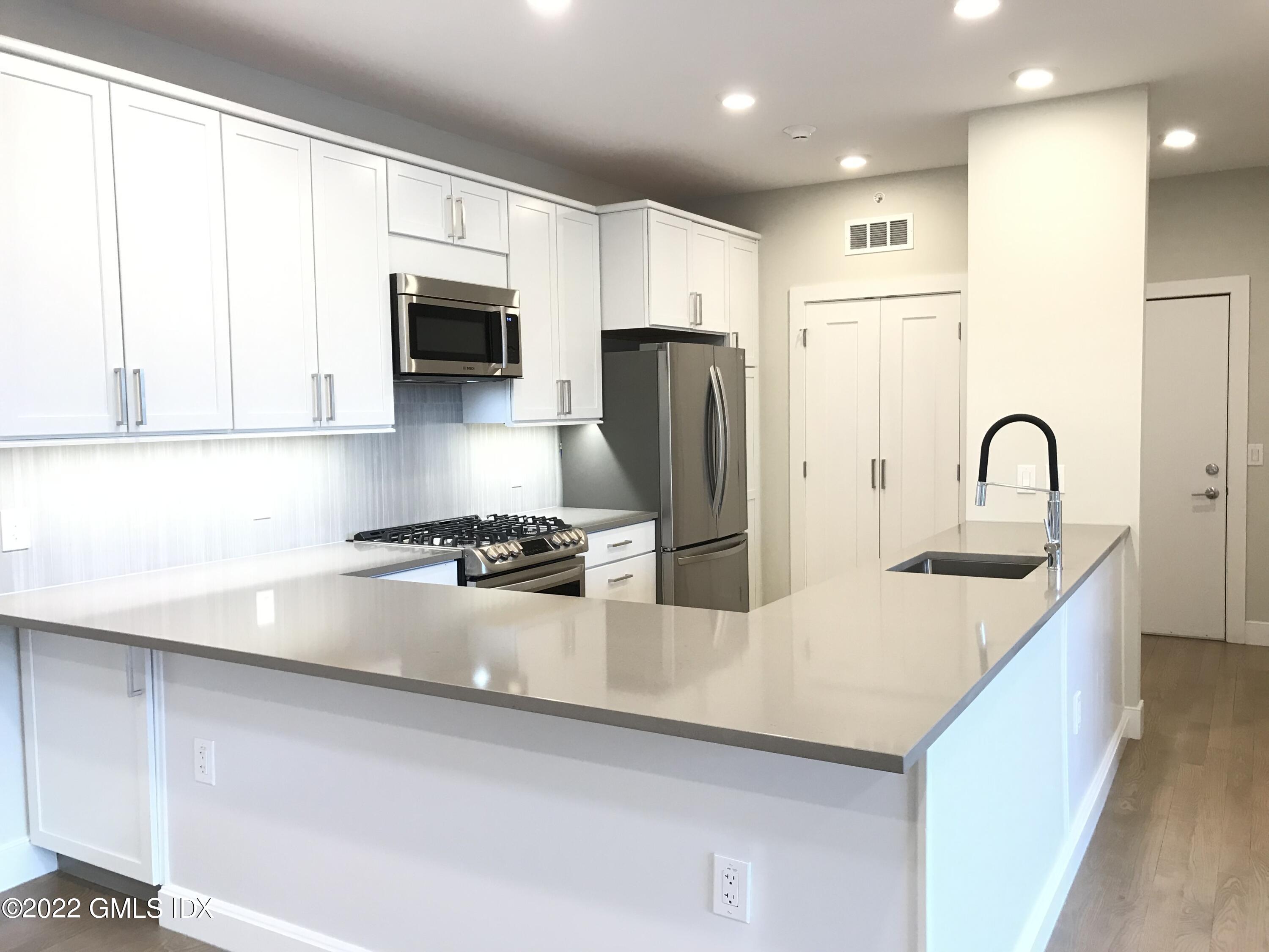 56 Old Field Point Road, Unit 4 Greenwich, CT 06830 - Photo 16 of 32 a kitchen with stainless steel appliances a refrigerator sink and microwave