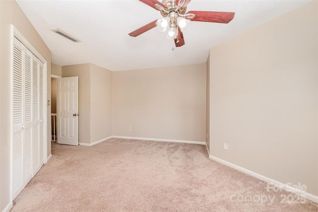 an empty room with large windows and ceiling fan