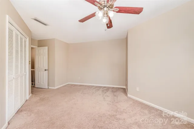 an empty room with large windows and ceiling fan