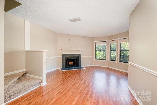an empty room with wooden floor fireplace and windows