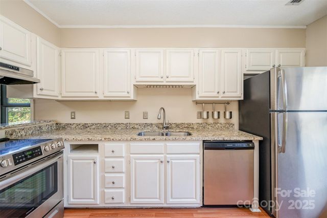 a kitchen with granite countertop a sink stove and refrigerator