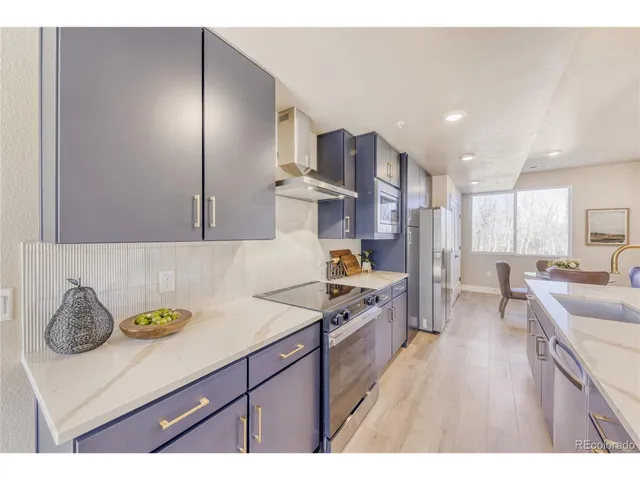 a kitchen with stainless steel appliances granite countertop a sink dishwasher stove and refrigerator with wooden floor