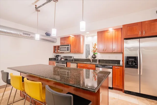 a kitchen with stainless steel appliances granite countertop a sink a stove and a refrigerator