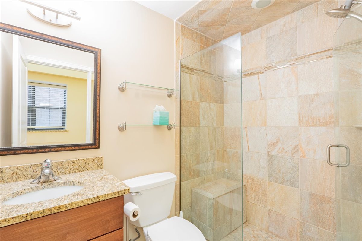 212 North Center Street, Unit 104 Bloomington, IL 61701 - Photo 10 of 22 a bathroom with a granite countertop sink toilet a mirror and shower