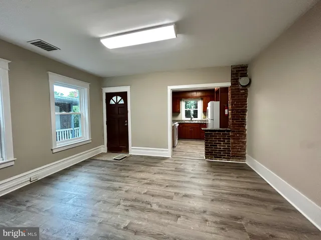 an empty room with wooden floor closet and windows