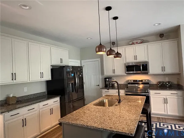 a kitchen with granite countertop a sink refrigerator and cabinets