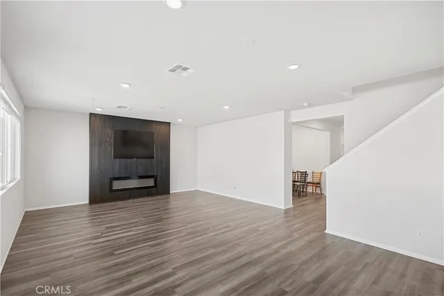 a view of an empty room with wooden floor and stairs