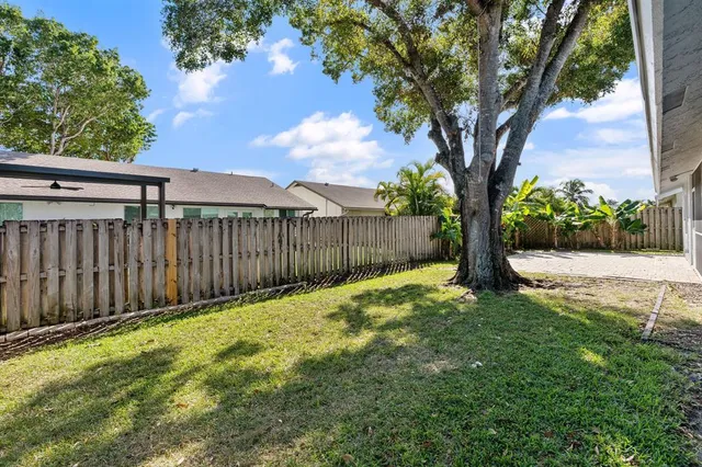 a view of a yard with a large tree and wooden fence
