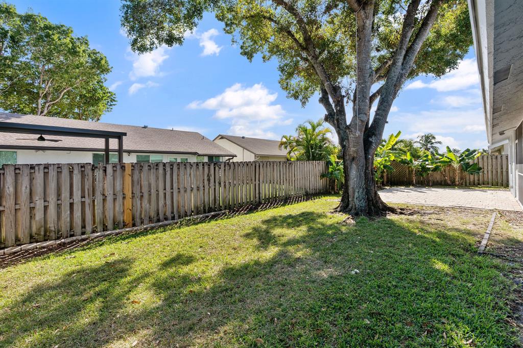 3240 Northwest 106th Avenue Sunrise, FL 33351 - Photo 19 of 21 a view of a yard with a large tree and wooden fence