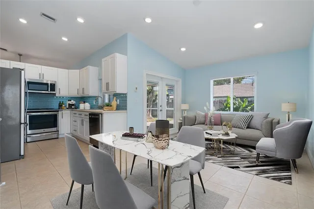 a living room with stainless steel appliances kitchen island granite countertop a dining table chairs microwave and view kitchen