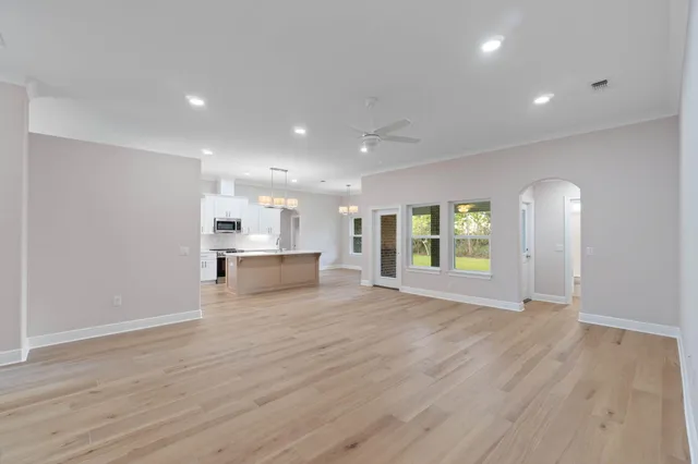 a view of an empty room with wooden floor and windows
