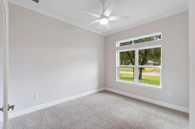 an empty room with windows and fan