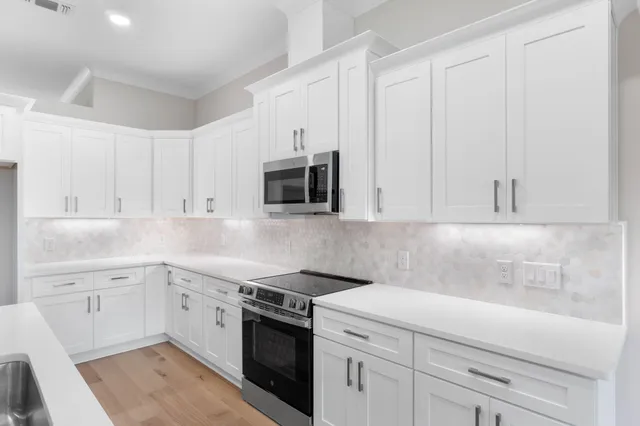 a view of kitchen with kitchen island wooden floor center island and stainless steel appliances